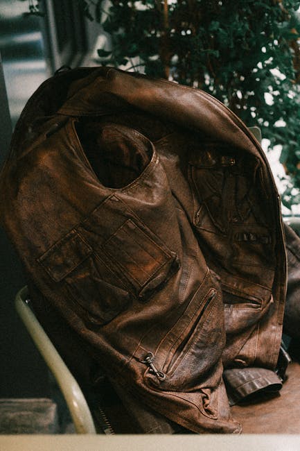 A vintage brown leather jacket draped over a chair indoors, capturing a rustic feel.